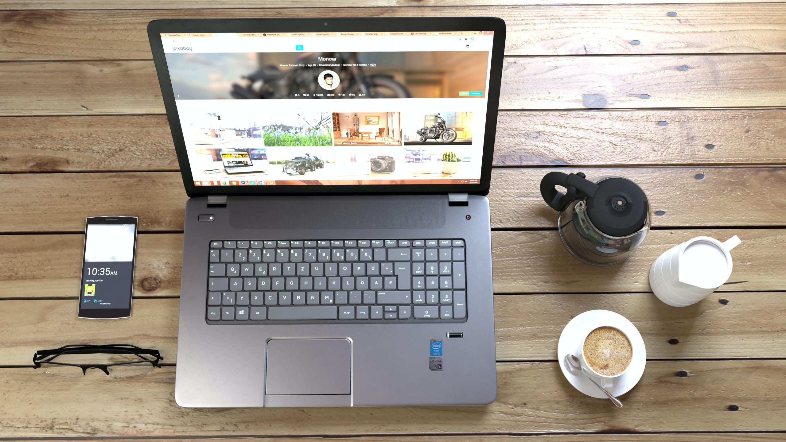 Silver laptop next to coffe cup smartphone and glasses